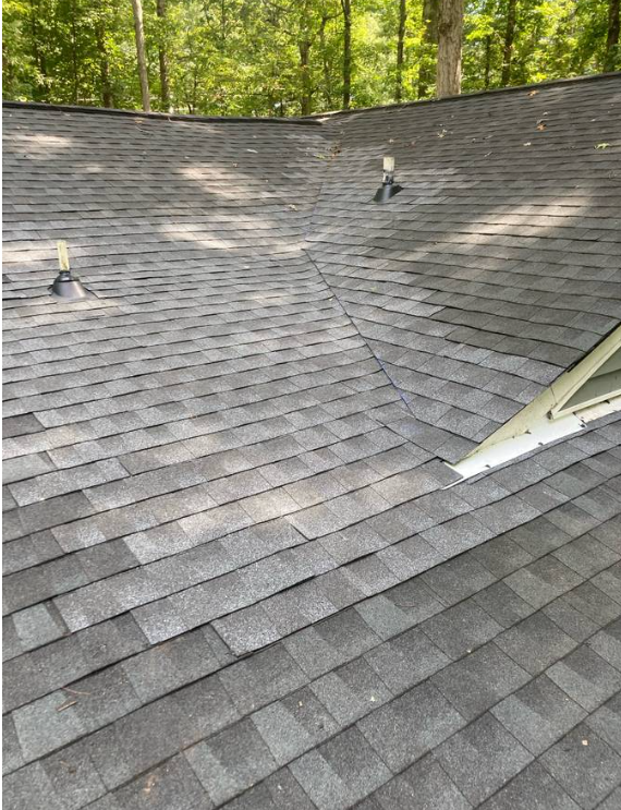 Close-up of a gray asphalt shingle roof valley with vent pipes