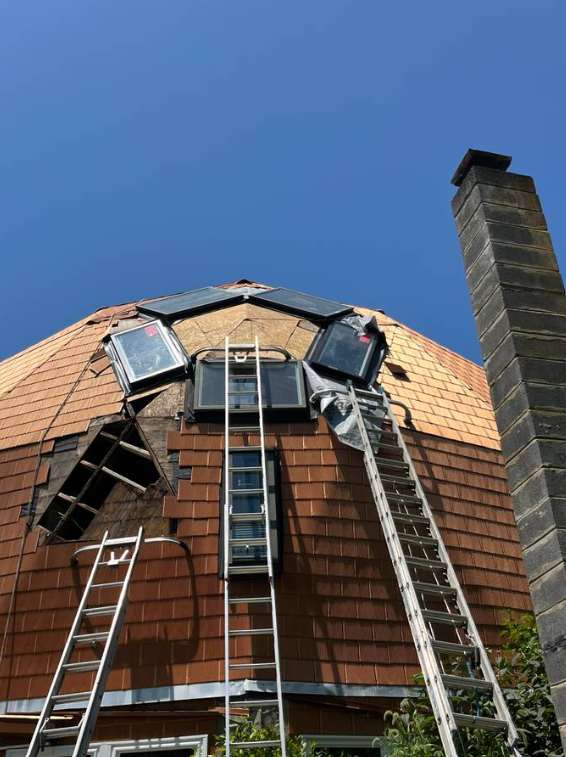 Ladders positioned on a dome home during a shingle roof installation